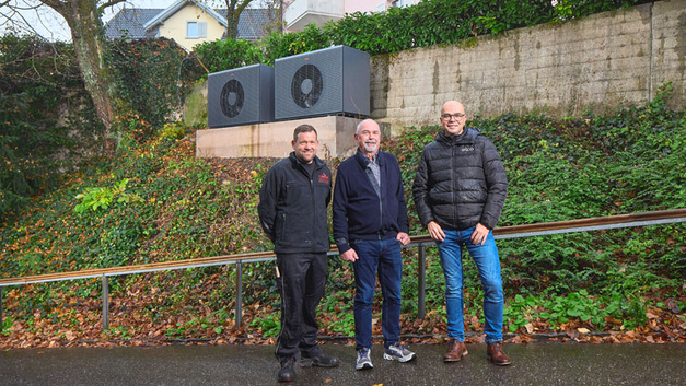 Markus Pfeiffer (Installateur), Urs Dejung (Bauherr) und Paulo Pereira (Elco) vor der neuen Kaskade. Die Aufstellung der beiden Wärmepumpen vor der bestehenden Stützmauer des Gartens minimiert die Schallemissionen noch weiter.